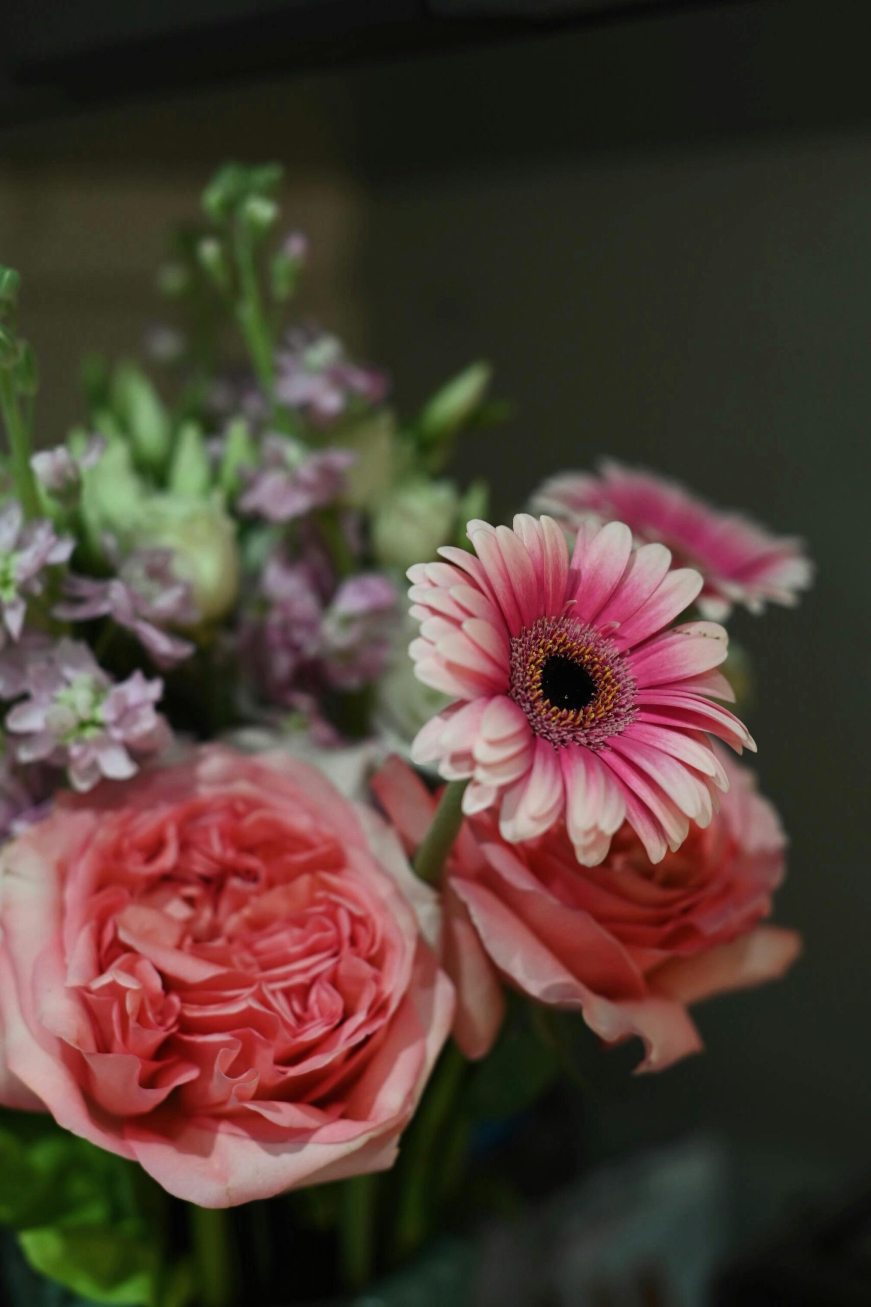 Close-up of vibrant pink roses and gerberas in a decorative bouquet.